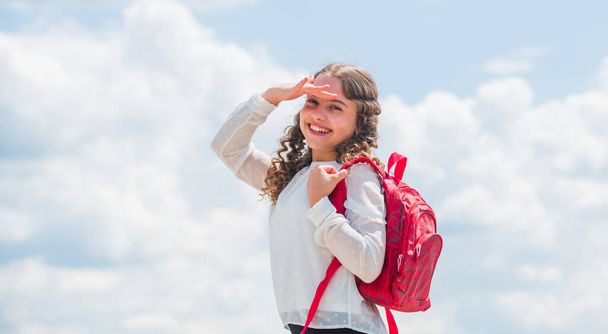 Outdoors classes. Successful schoolgirl. Good day for studying. Free education. Little child smiling going to school. Knowledge day. Happy girl with school backpack sky background. Back to school - Fotó, kép