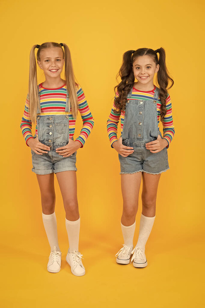 Trendy and fancy. Little girls wearing rainbow clothes. Matching outfits. Fashion shop. Must have accessory. Vibrant colors. Modern fashion. Kids fashion. Girls long hair. Cute children same outfits - Photo, image