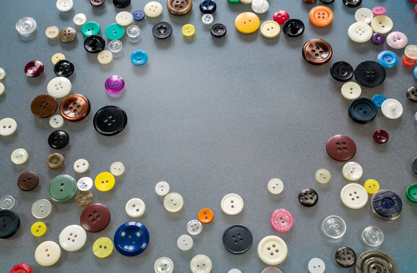 多くの多色のボタンがテーブルの上にあり、中央に空のスペースを形成します。 - 写真・画像