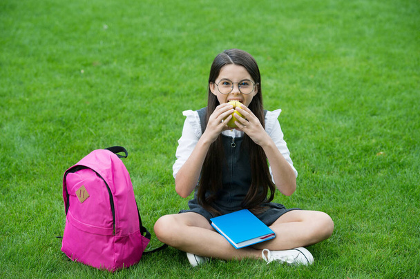 Food for healthy tooth. Little kid eat apple sitting on green grass. School snack. Health education. Dental diet. Dental health. Oral hygiene. Dental care. Preventing cavities. Pediatric dentistry - Fotó, kép