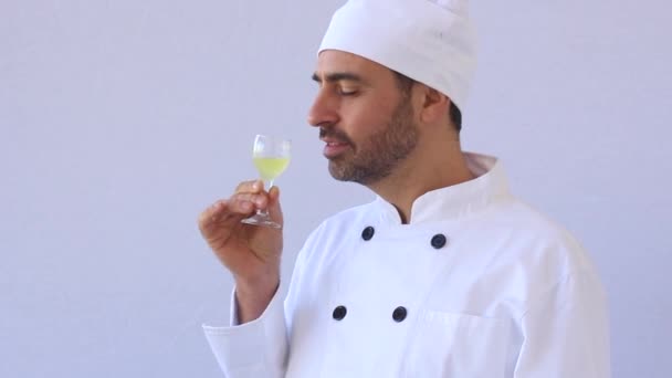 Bearded middle-aged chef in white toque and uniform standing looking at the camera with copyspace on white - Metraje, vídeo