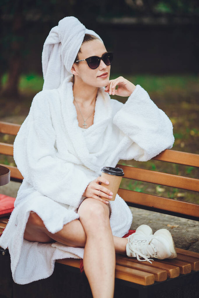 Young beautiful girl in a robe sits drinking coffee - Photo, image