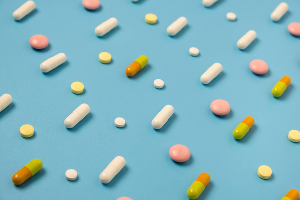 Großaufnahme von vielen verschiedenen Pillen, die im Muster auf blauem Hintergrund angeordnet sind. - Foto, Bild