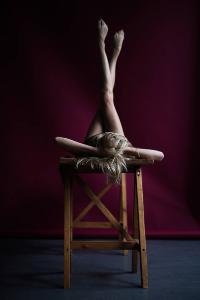 young woman lies on  wooden table raising her legs - Foto, Imagen