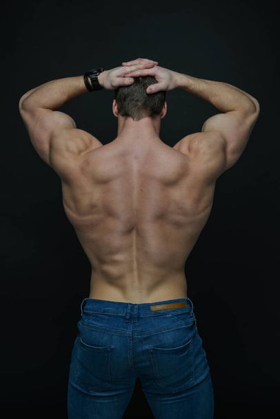 Gespierd mannelijk model tonen zijn rug - Foto, afbeelding