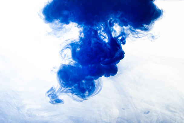 A cloud of blue paint released into clear water. Isolate on a white background. - Photo, Image