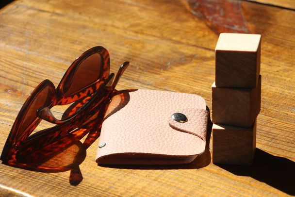 木製のテーブルの上にサングラスとピンクの革の財布。リラックスして休暇夏休みのコンセプト - 写真・画像