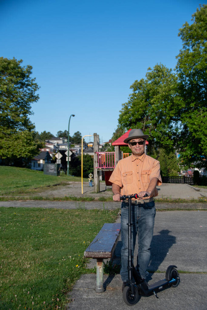 Мужчина средних лет, стоящий с электрическим скутером. Ванкувер - Фото, изображение