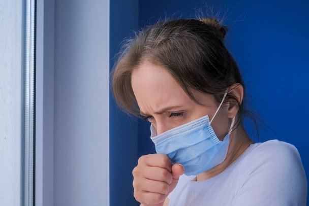woman with face mask suffering from coughing, looking out of window - close up - Photo, Image