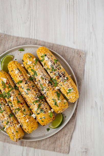 Homemade Elote Mexican Street Corn on a plate on a white wooden background, top view. Flat lay, overhead, from above. Space for text. - 写真・画像