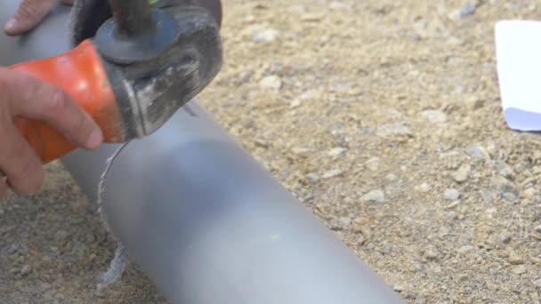 ZAMKNIJ SIĘ: Nierozpoznawalny hydraulik używa szlifierki kątowej do cięcia rur kanalizacyjnych pvc. - Materiał filmowy, wideo