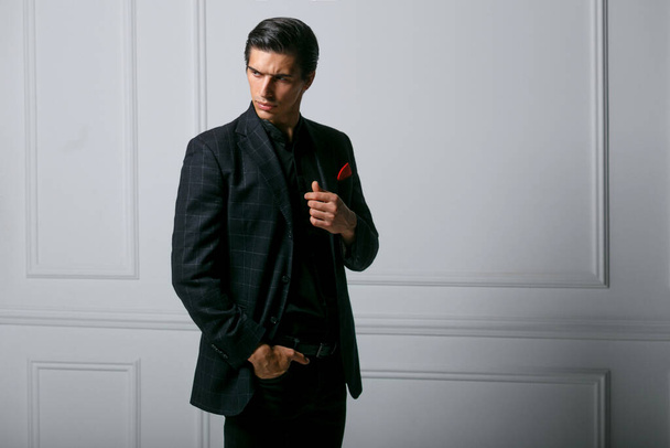 Side view of a sexy confident young man in black suit with red silk scarf in pocket, over white background. - 写真・画像