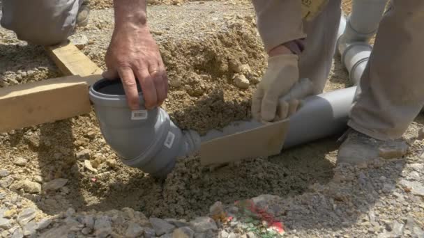 Skupina stavitelů pohřbívá širokou plastovou kanalizační trubku s betonem. - Záběry, video