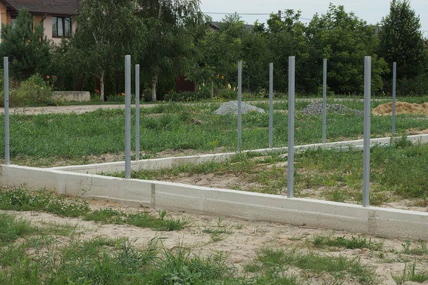 fundación de hormigón gris con pilares de hierro al aire libre en un sitio de construcción en hierba verde - Foto, imagen