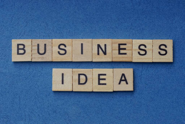 frase business idea in piccole lettere quadrate di legno con carattere nero su sfondo blu - Foto, immagini
