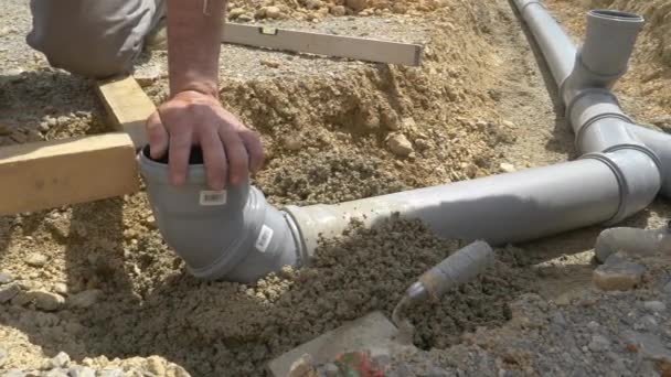 FERMETURE : Les plombiers utilisent un niveau et du béton frais pour enterrer un tuyau d'égout large. - Séquence, vidéo