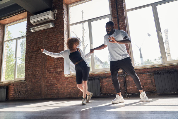 Happy young couple practicing modern dancing in studio - Foto, imagen