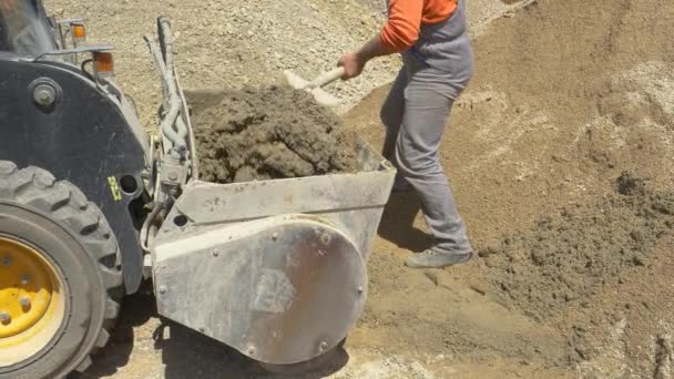 Pracovník používá lopatu, aby míchal míchání betonu v zadní části buldozeru. - Záběry, video