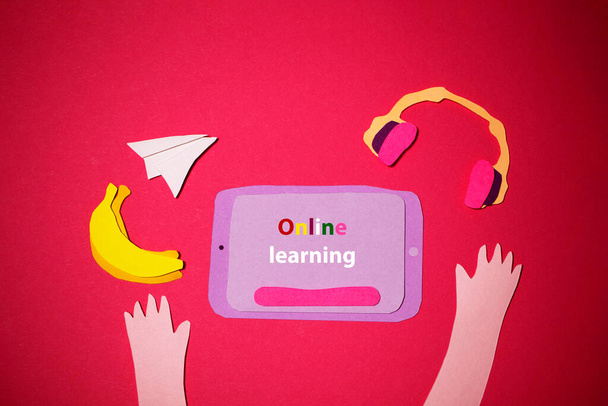 Tablette, les écouteurs et les fruits sont découpés dans du papier coloré sur un fond rouge pour l'apprentissage en ligne. Je retourne à l'école. La photo de l'art du papier a été faite pour votre design artisanal. - Photo, image