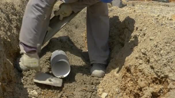 FERMER : Builder nettoie l'excès de gravier avec une spatule avant de poser un nouveau tuyau - Séquence, vidéo