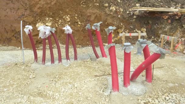 CLOSE UP: Long red plastic conduits stick up in the air from the gravel ground - Footage, Video
