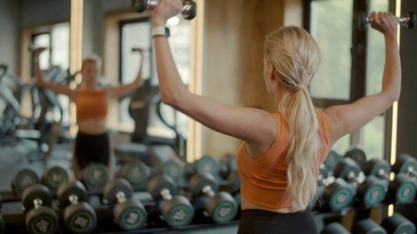 Vážně fit holka dělá blbeček biceps kadeře v klubu. Sportovní žena trénink v posilovně - Fotografie, Obrázek