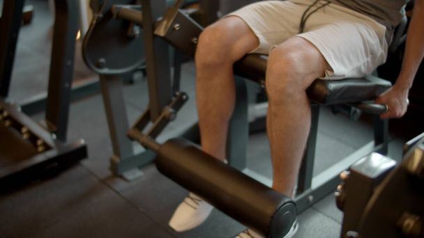 Unbekannter Bodybuilder macht Beinverlängerung im Sportverein. Beintraining im Fitnessstudio - Foto, Bild