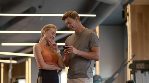 Beau couple en forme flirtant à la salle de gym. Fit man écriture numéro de téléphone dans le club de sport
 - Photo, image