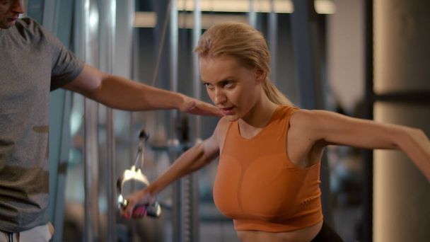 Energetische koppel workout in sportclub. Sport vrouw maken arm krullen in de sportschool - Foto, afbeelding