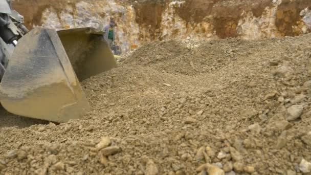CERRAR: La excavadora avanza y recoge un cubo lleno de rocas húmedas. - Metraje, vídeo