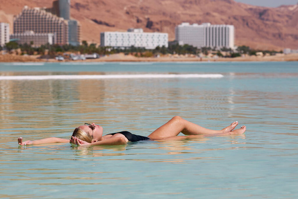 Young woman is relaxing in dead sea - 写真・画像