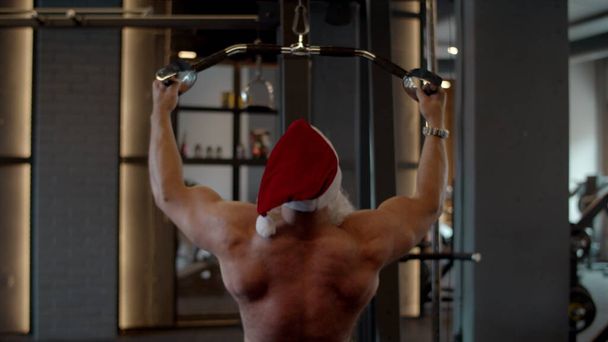 Aktiver Weihnachtsmann beim Bankdrücken im Fitnessstudio. Sportlerausbildung im Sportverein - Foto, Bild