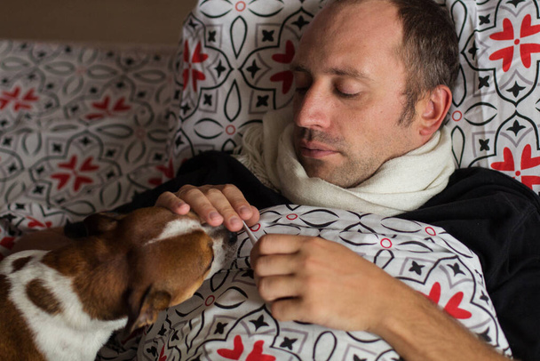 Hombre acostado en la cama con el perro y la celebración de thermometr - Foto, imagen