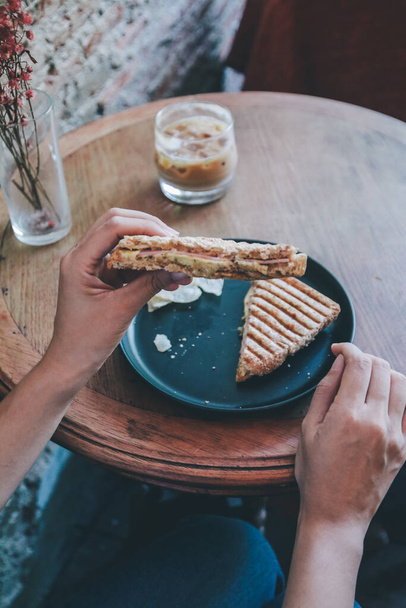 Femme mangeant grill sandwich jambon fromage et salade (laitue, jambon, fromage, tomate et croustille de pomme de terre) avec une tasse de café pour le repas du petit déjeuner le matin. - Photo, image
