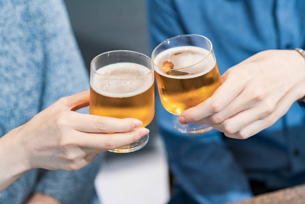 nuori mies ja nainen paahtaminen lasillisella olutta kotona - Valokuva, kuva