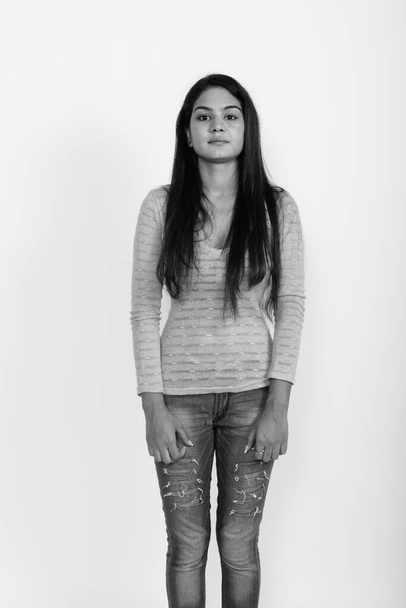 Studio shot of young beautiful Indian woman against white background in black and white - Foto, immagini