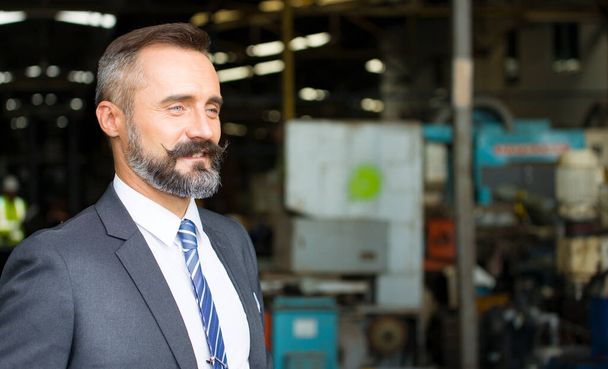 Kafkas sakallı yakışıklı iş sahibinin portresi fabrikasının önünde duruyordu ve gülümseyerek ön tarafa baktı.. - Fotoğraf, Görsel