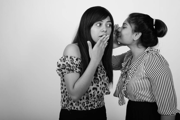 Estúdio tiro de duas jovens mulheres persas como amigos juntos contra fundo cinza em preto e branco - Foto, Imagem