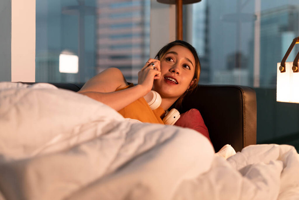 Schöne Mischlingshündin telefoniert nachts auf einem Bett. - Foto, Bild