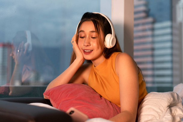 Красива змішана раса жінка насолоджується послухати музику з бездротовими навушниками вночі
. - Фото, зображення