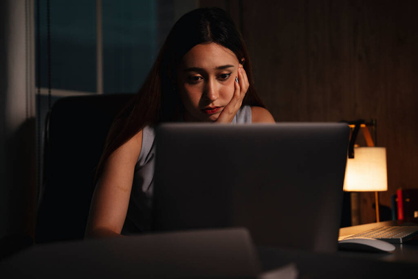 Piękne mieszane rasy kobieta pracuje nadgodziny na laptopie w nocy. - Zdjęcie, obraz