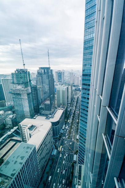 Макати, Филиппины - Вид на авеню Айяла и здания из окна офисного здания. Синее тонированное окно и пасмурная погода. Нейтральные цвета. - Фото, изображение