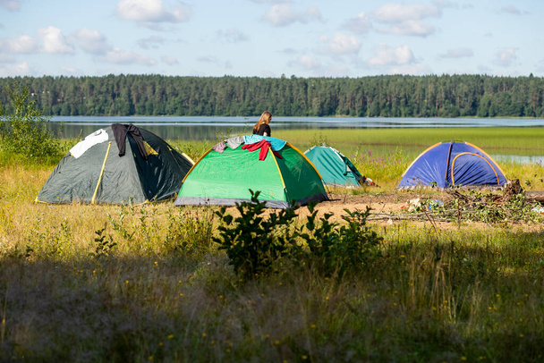Namiot rozstawiony na nierównym polu namiotowym, na skraju jeziora.Camping kolorowy namiot na brzegu jeziora, namiot turystyczny na brzegu stawu. koncepcja turystyki aktywnej - Zdjęcie, obraz