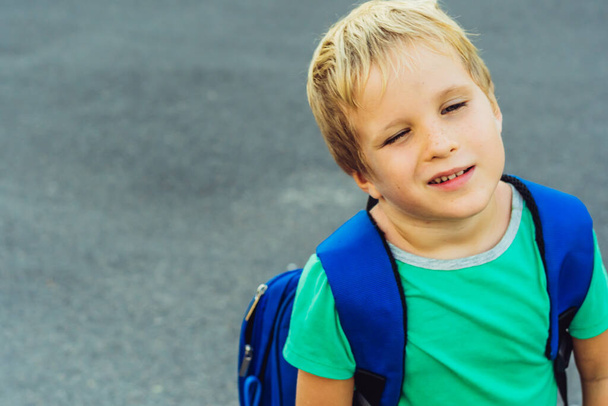 Funny mischievous cute blond boy with freckles blue backpack from school or kindergarten, artistic emotions facial expression. Micro moments simple joys happy childhood, education problems psychology - Photo, Image