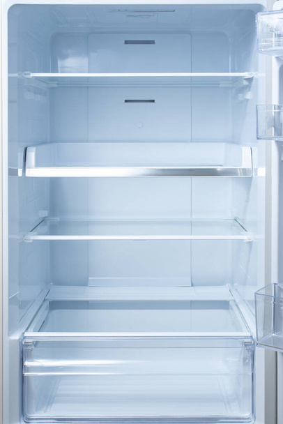 Empty open fridge with shelves, refrigerator. mockup background empty shelves for your products. open fridge shelf. Interior of an empty open white refrigerator. Vertical - Foto, Imagen