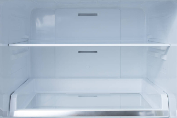Shelves in empty open white fridge. Background empty shelves in the refrigerator. Weight loss diet concept. - Foto, Imagen