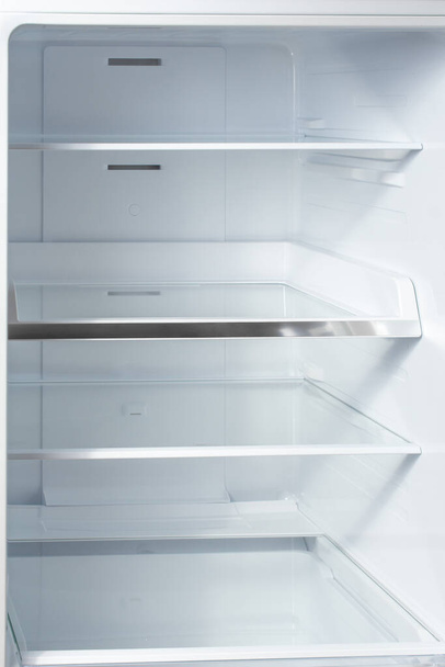 Clean empty shelves in white refrigerator. Empty open fridge with shelves, refrigerator. shelves in empty open white fridge background. Vertical - Foto, Imagen