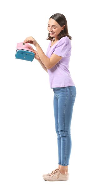 Mujer joven poniendo dinero en la cartera sobre fondo blanco - Foto, Imagen