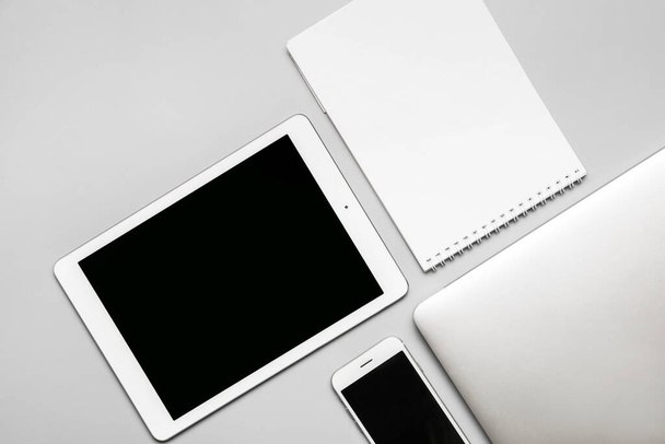 Modern devices with notebook on grey background - Foto, Bild