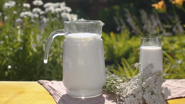 Молоко и цветы на столе в саду - Кадры, видео